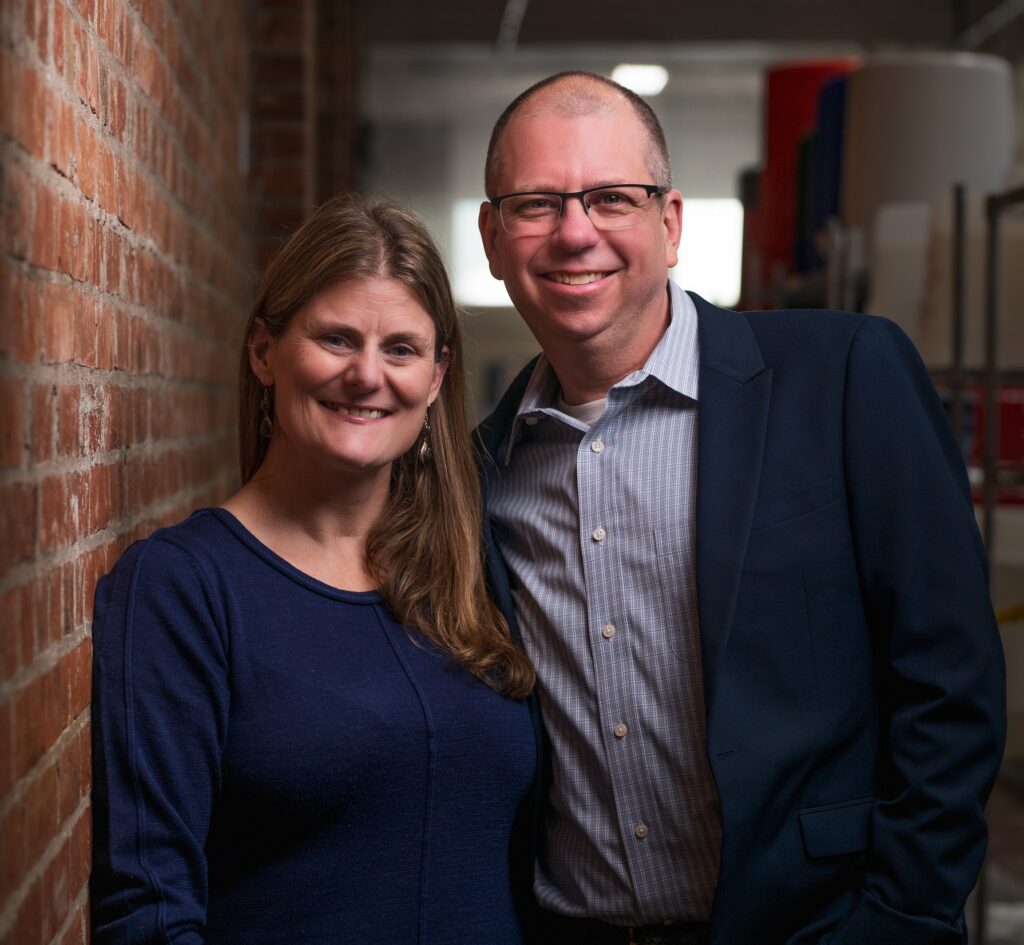 Liz and Glenn posing together against a brick wall.