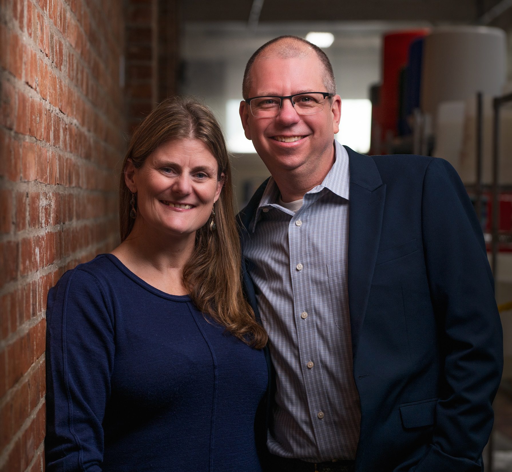 Liz and Glenn posing together against a brick wall.