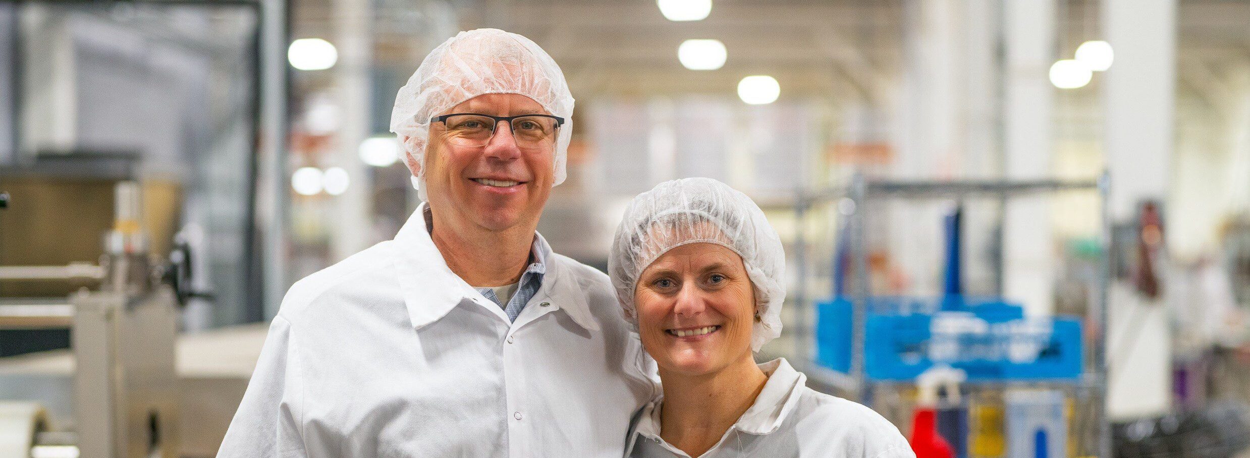 Snackteva co-founders Glenn and Liz Ward in PPE inside a food manufacturing facility