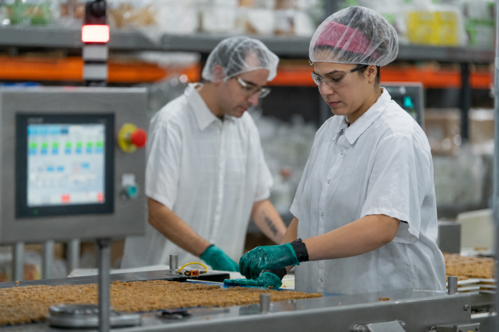 Two production workers verifying settings at a slab line control panel