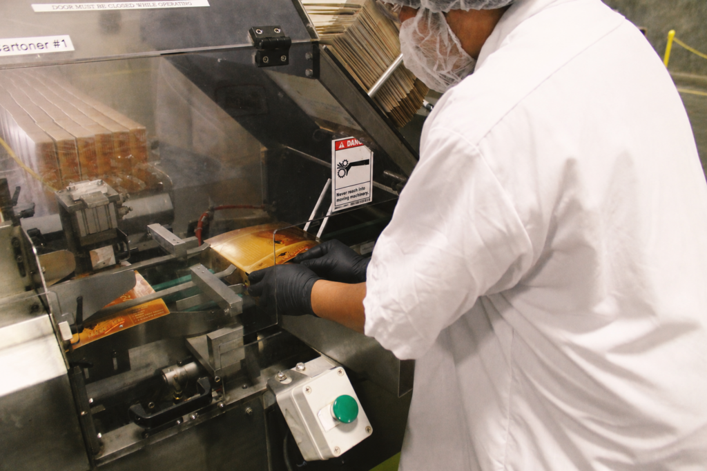 A factory worker cartoning BumbleBar bars on the production line — the kind of operation behind our food product recall story.