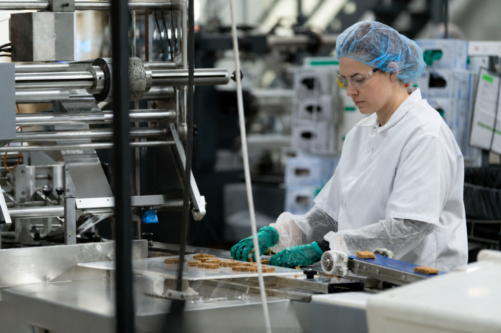 Food production worker operating a flow-wrapper packaging line in a co-packing facility